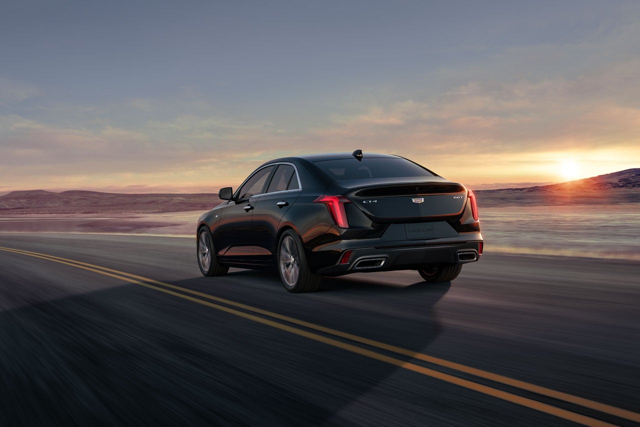 Three Quarters Rear View of a Black 2026 CT4 Driving Down a Desert Road