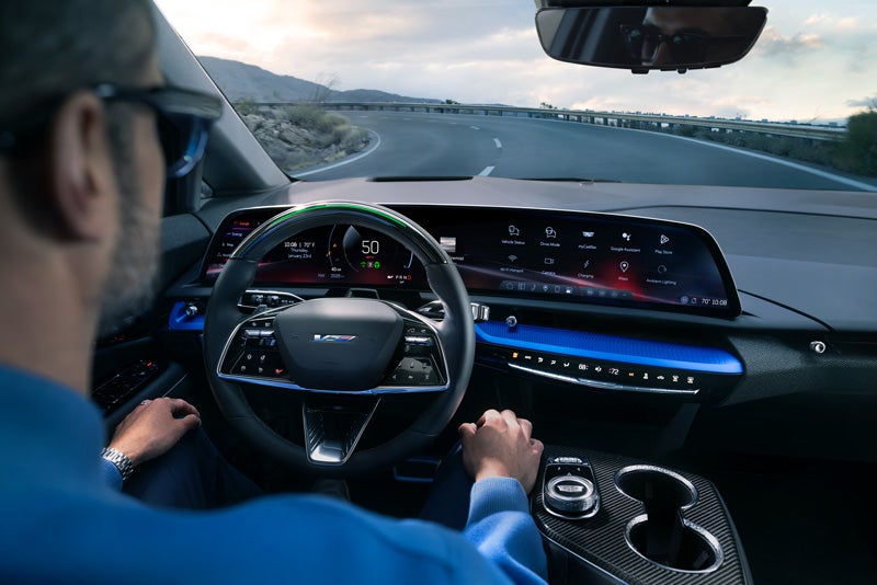 Front View of the 2026 OPTIQ-V Driving Through the Dusk Utilizing its Headlights | Mitch Hall Cadillac in Lamesa TX